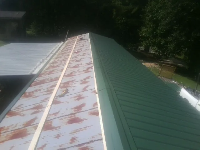 Old rusted panels beside newly installed green metal roofing — Wind Damage Roof Repair by Roofing Brothers in Lawrence