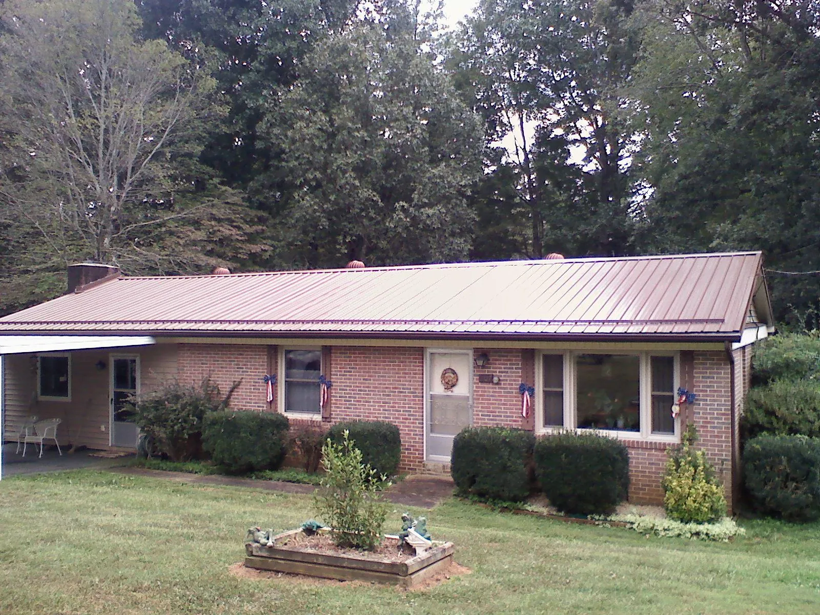 Bronze metal roof on a brick ranch home with a carport in Lawrence