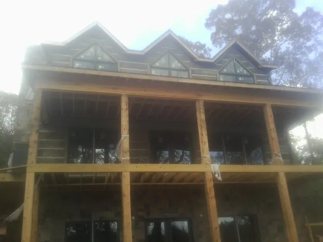 Dormers and porch framing on a large log home under construction — Roof Coating work by our crew in Lawrence